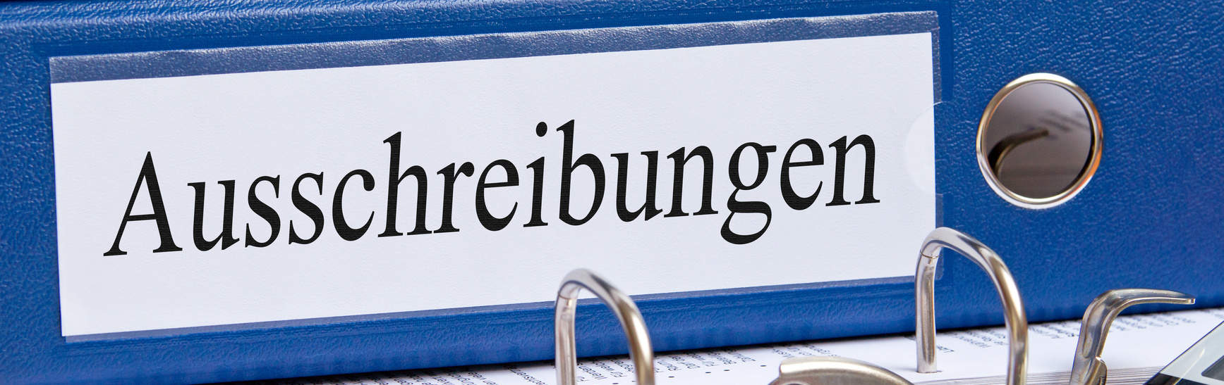 blauer Ordner mit Beschriftung Ausschreibungen - bildlich für Versicherungsberatung im öffentlichen Sektor